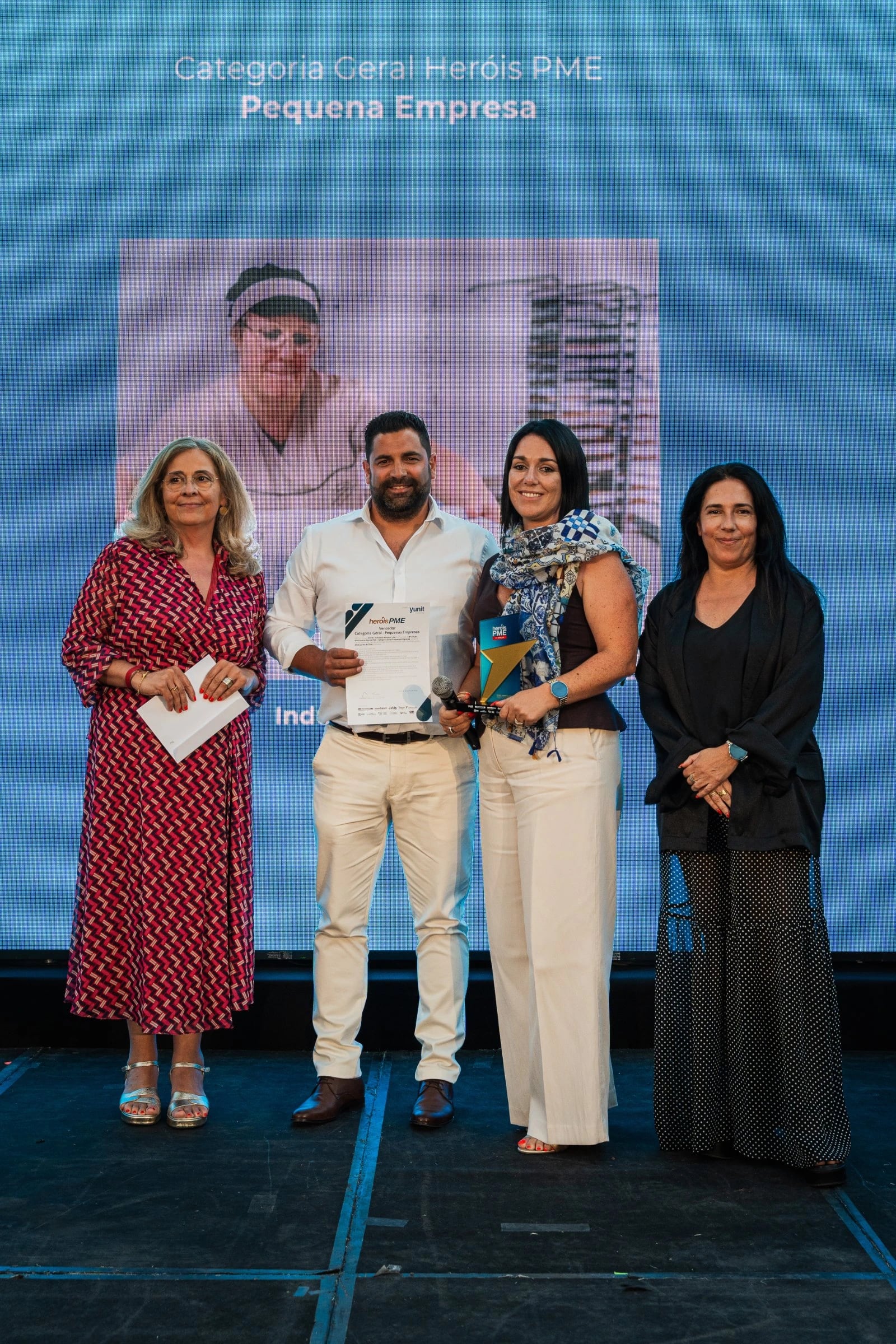 Quatro pessoas em palco com diploma e troféu, ecrã atrás com "Categoria Geral Heróis PME — Pequena Empresa"