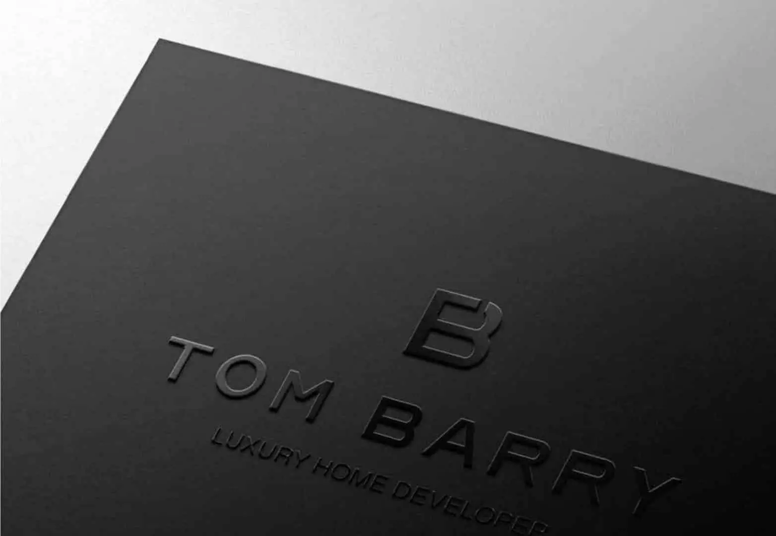 TOM Barry black business card with the monogram blind-embossed.