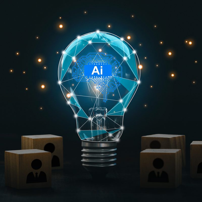 Lâmpada brilhante com elementos digitais representando inteligência artificial no centro, cercada por blocos de madeira com ícones de pessoas, simbolizando tecnologia e inovação em ambientes corporativos.